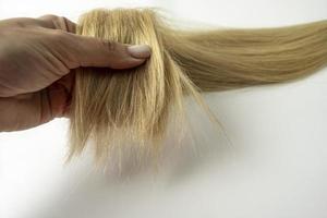 en kvinna innehav en blond hår lager i henne hand foto