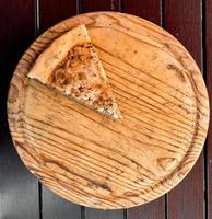 ett sista skiva av pizza på en trä- bricka. foto