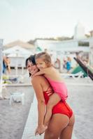 ung mor ger dotter piggyback rida på de strand foto