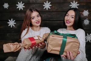 två skön flickor erbjudande gåvor till kamera foto