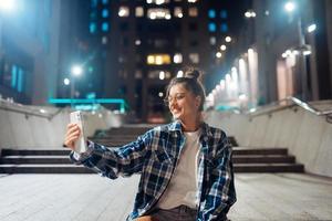 kvinna talande via video ring upp i de natt stad foto