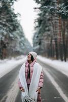 porträtt av en skön caucasian kvinna på en väg genom snöig skog foto