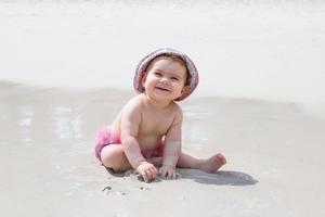 förtjusande liten flicka är spelar med sand på strand nära till hav. sensorisk utveckling för barn utomhus. foto
