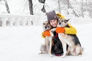 porträtt av skön leende ung kvinna med henne två hundar i en snöig vinter- parkera. foto