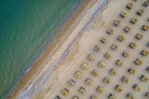 antenn se av ett Fantastisk strand med trä- paraplyer, och lugna hav. foto