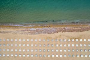 antenn se av ett Fantastisk strand med vit vardagsrum stolar, och turkos hav. foto