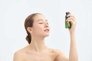 ung kvinna applicering termisk vatten på ansikte mot vit bakgrund. kosmetisk produkt foto