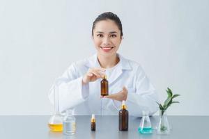 kvinna hudläkare innehav flaska av hud vård produkt över tabell, närbild foto