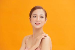 skönhet porträtt av ett attraktiv ung topless kvinna isolerat över gul bakgrund foto