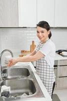 kvinna tvättning händer i kök handfat foto
