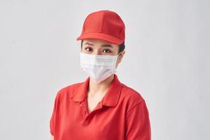 leverans kvinna bär röd keps och coronavirus skydd mask med en Lycklig och Häftigt leende på ansikte. tur- person. foto