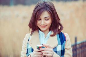 kvinna sms. närbild ung glad le gladlynt vacker kvinna tittar på mobiltelefon läsning skicka sms isolerade park stadsbild utomhus bakgrund. positivt ansiktsuttryck mänskliga känslor