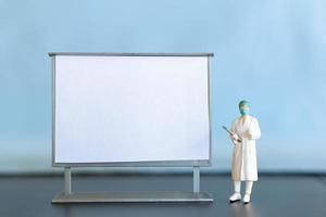 miniatyr- läkare stående med tom vit styrelse foto