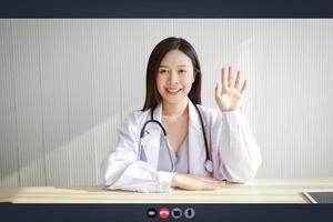 närbild på en dator skärm, en skön asiatisk kvinna läkare behandlar en patient via uppkopplad video ringa upp. begrepp av medicinsk service. rådfråga en sjuk person uppkopplad under de coronavirus spridning foto