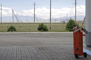 röd tank på en gas station i Kirgizistan, med kraft rader och de bergen i de bakgrund foto