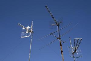 tre antenner mot en blå himmel foto