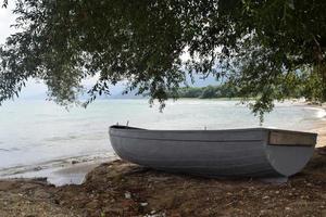 ett tömma rodd båt är stående på de Strand av de sjö foto