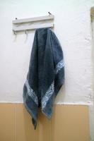 mörkblå våt handduk hängde på badrumsväggen foto