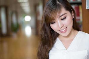 vacker asiatisk kvinnlig student läser bok i biblioteket