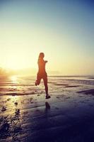 ung fitness kvinna kör på sunrise beach