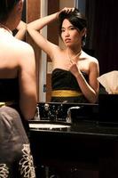 asiatisk kvinna som tittar på sig själv i fåfänga spegel foto