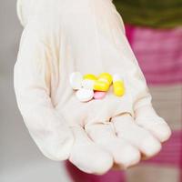 få tabletter i patient handskar hand foto