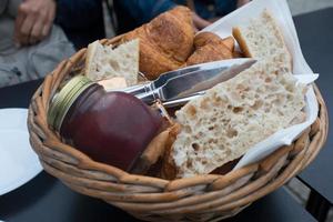 frukost korg med bröd, croissanter, Smör och confiture foto
