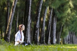 kvinna som avkopplande utövar meditation i tallskogen för att uppnå lycka från inre frid visdom för ett hälsosamt sinne och själskoncept foto