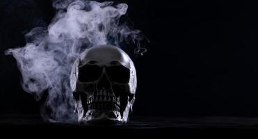 halloween mänsklig skalle på ett gammal trä- tabell över svart bakgrund. form av skalle ben för död huvud på halloween festival som visa Skräck ondska tand rädsla och skrämmande med dimma rök, kopia Plats foto