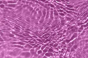 defokusering suddig transparent lila färgad klar lugna vatten yta textur med stänk, bubbla. lysande lila vatten krusning bakgrund. yta av vatten i simning slå samman. tropisk lila vatten Färg. foto
