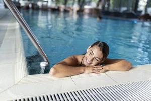 skönhet och kropp vård. sensuell ung kvinna avkopplande i inomhus- spa simning slå samman. foto