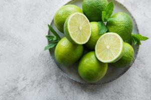 gröna limefrukter med färska myntablad på tallrik foto