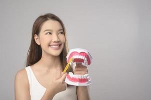 ung leende kvinna innehav tandborste över vit bakgrund studio, dental sjukvård och ortodontisk begrepp. foto