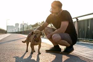 ung stilig man är gående med hans hund i de morgon- på tömma gata av stad. foto