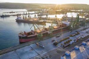 antenn se från de Drönare av en stor fartyg läser in spannmål för exportera i de hamn. vatten transport foto