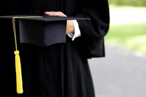 gradering, stänga upp studerande innehav hatt tofs röd med diplom certifikat i hand under början Framgång examinerade av de universitet, begrepp utbildning congratulation ceremoni grad. foto