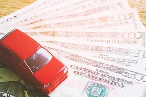 topp se liten röd bil över en massa av pengar dollar euro räkningar, kosta beräkning kostnader för lån kostar och betalningar avbetalning begrepp. foto