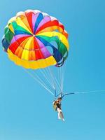 flicka parascending på fallskärm i blå himmel foto