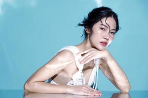 attraktiv ung våt hår asiatisk kvinna modell med perfekt färsk hud på under vattnet simulering av belysning ansikte vård ansiktsbehandling behandling kosmetologi plast kirurgi härlig flicka porträtt i studio foto