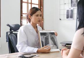 läkare som visar röntgen resultat till patient i klinik. foto