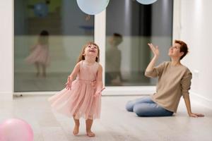 mor och söt liten dotter spelar med ballonger foto