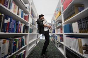 studerande innehav massa av böcker i skola bibliotek foto