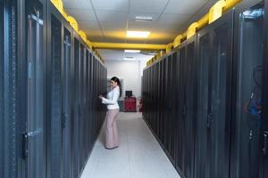 kvinna ingenjör arbetssätt på en läsplatta dator i server rum foto