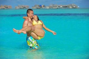 Lycklig ung par njuter sommar på strand foto