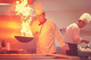 kock håller på med flambe på mat foto