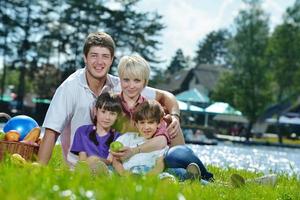 Lycklig familj spelar tillsammans i en picknick utomhus foto