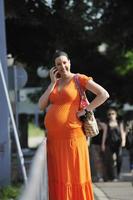 Lycklig gravid kvinna talande förbi mobiltelefon foto
