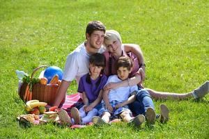 Lycklig familj spelar tillsammans i en picknick utomhus foto