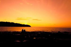 silhuett av en ung romantisk par med solnedgång i de mitten och strand bakgrund foto