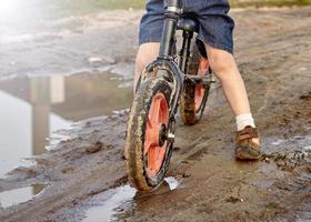 en barn på en cykel rider genom de lera foto